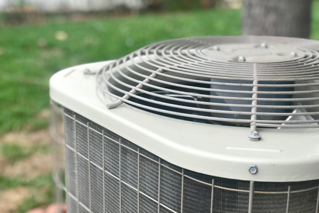 Close-up angled view of an AC condenser unit outside a home.